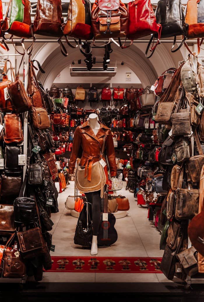 A vibrant indoor leather goods store with a mannequin dressed in leather clothing, surrounded by various bags.